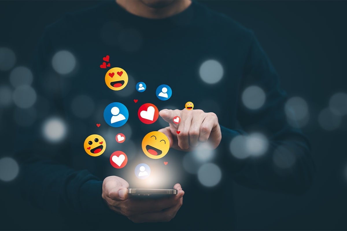 Un hombre sostiene un teléfono celular del que salen emojis de intereses segmentados.