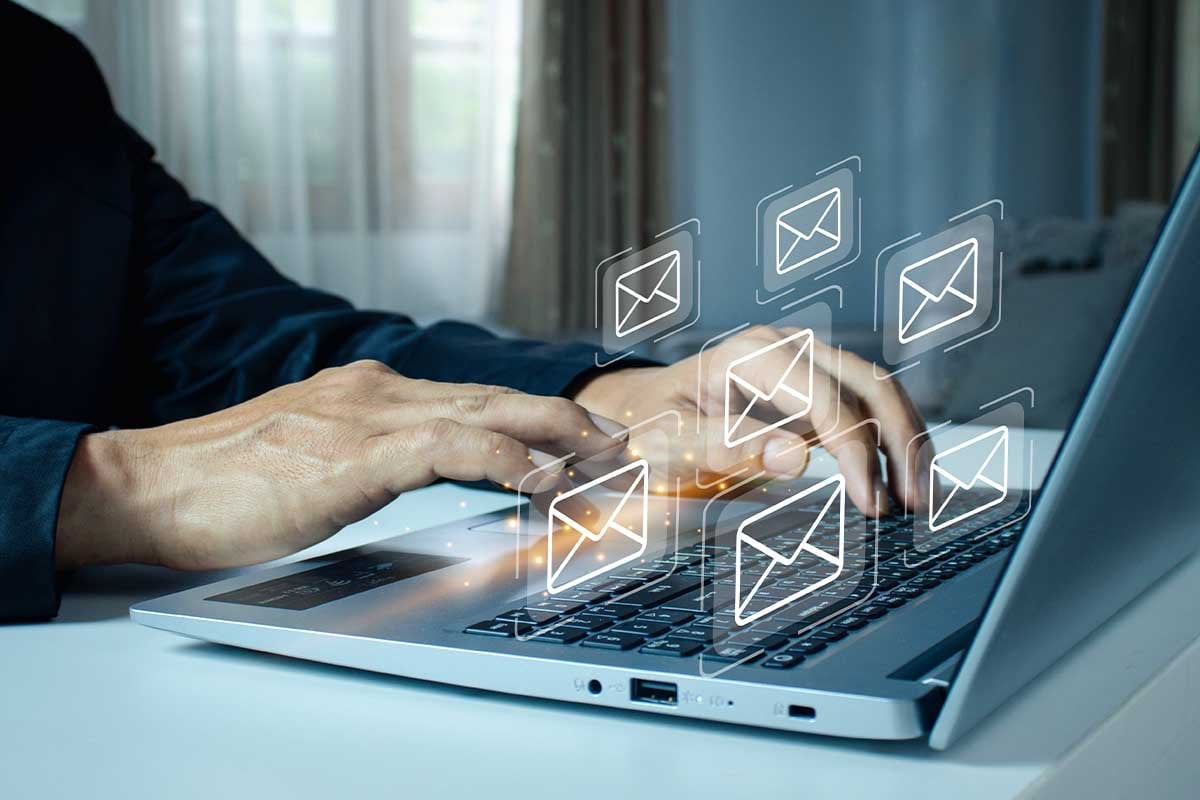 Un hombre está usando una computadora portátil para revisar sus contactos de correo electrónico.