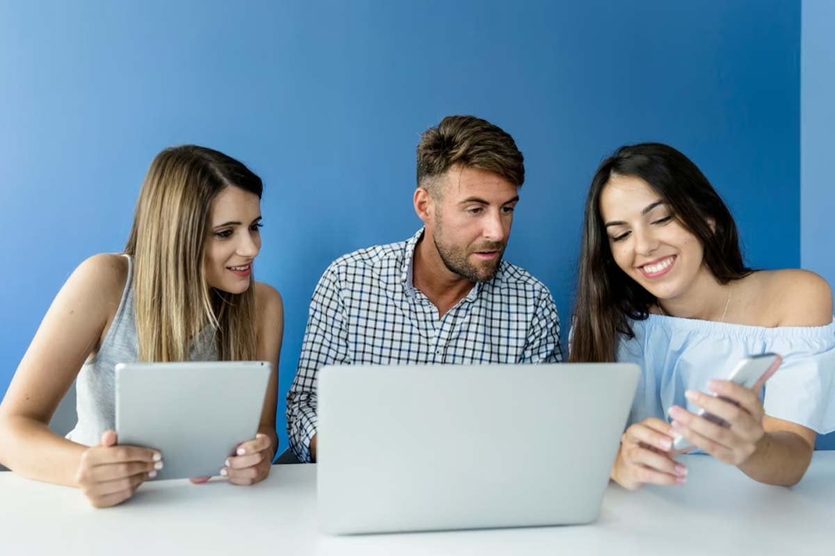 Tres personas discutiendo diferentes tipos de páginas de inicio mientras miran una computadora portátil en una mesa.