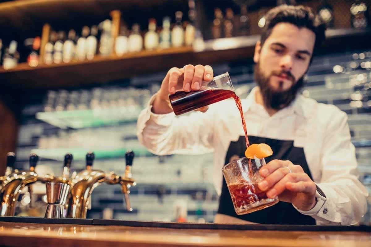 Un cantinero sirviendo una bebida en un bar de pequeñas estrategias.