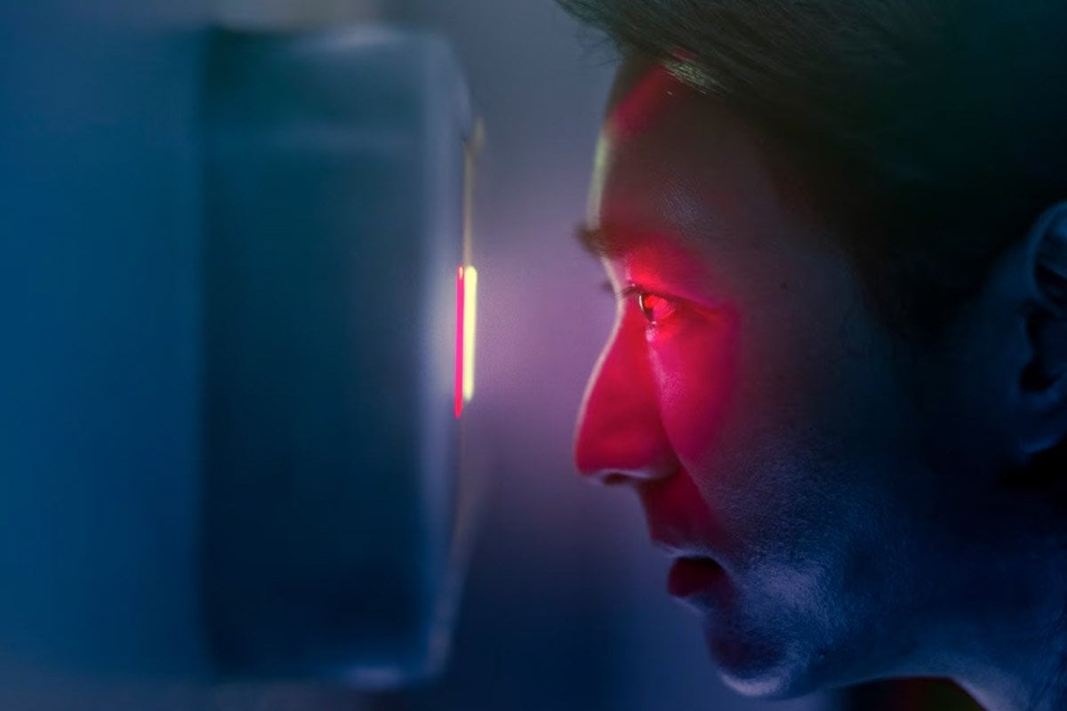 Un hombre observando una luz roja en una habitación con poca luz.