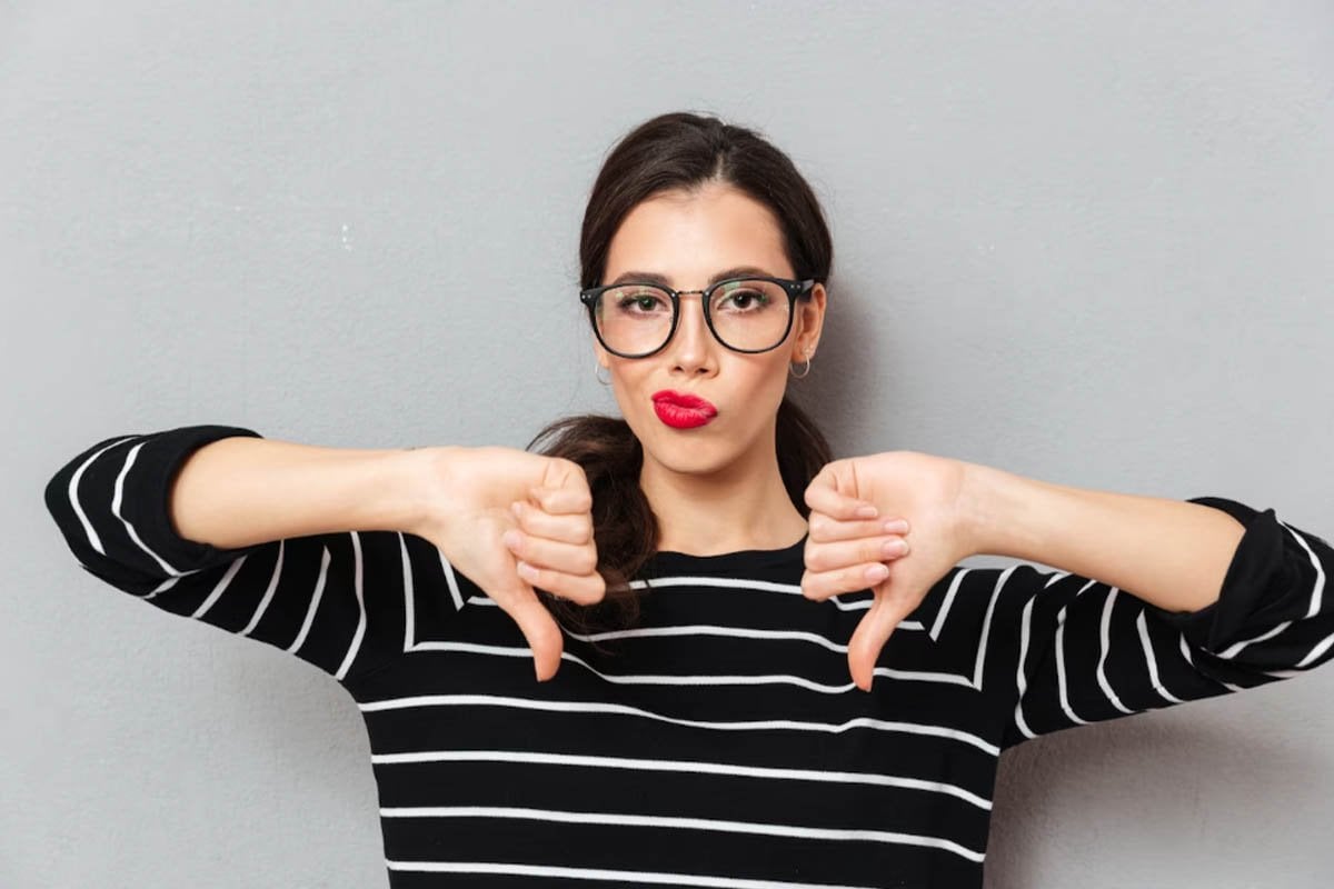 Una mujer con anteojos que expresa su desaprobación a través de un pulgar hacia abajo en respuesta a los anuncios de Facebook.