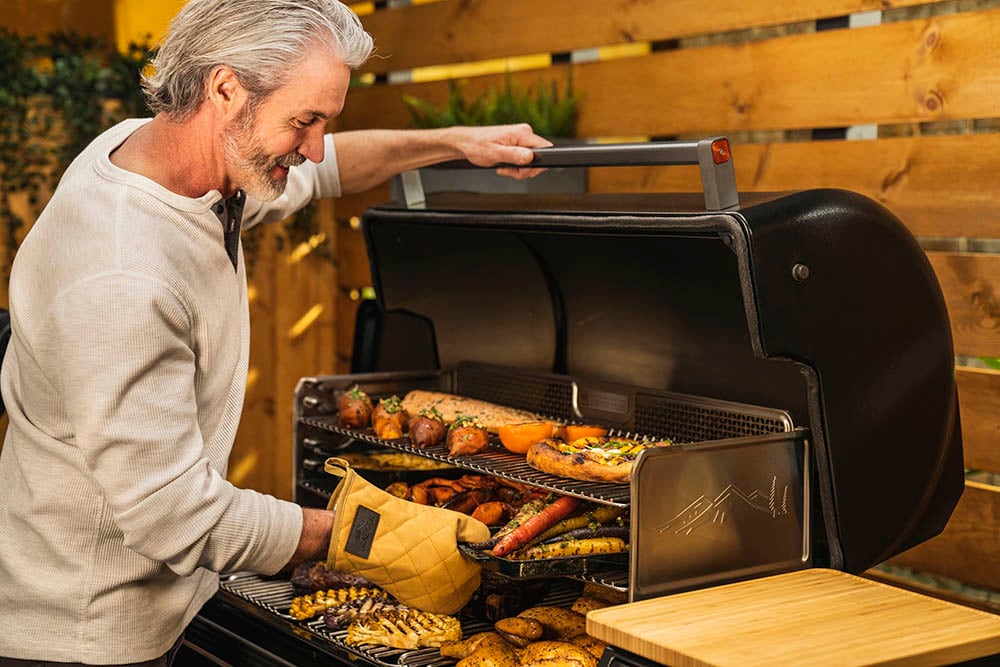 Timberline XL Lifestyle Grill being used by man grilling a bunch of meats