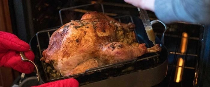 turkey being placed in the oven on a braising pan