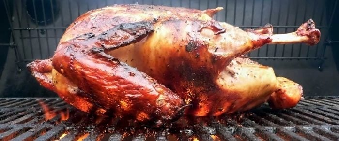 a turkey cooking on a grill