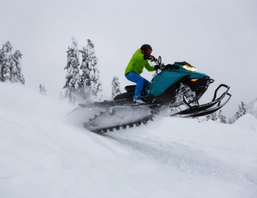 Adventurous Man Riding a Snowmobile in white snow