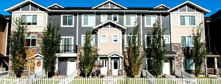 a house with a fence in front of a brick building