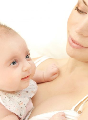 A woman gazes lovingly at the baby in her arms, who looks upwards with a curious expression. They are both bathed in soft, natural light. A woman gazes lovingly at the baby in her arms, who looks upwards with a curious expression. They are both bathed in soft, natural light.