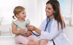 Pediatrician carrying out a checkup on a young child with a stethoscope. Pediatrician carrying out a checkup on a young child with a stethoscope.