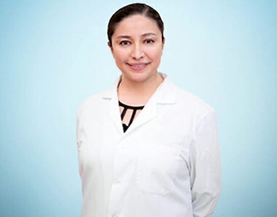 A confident healthcare professional wearing a white lab coat against a blue background.