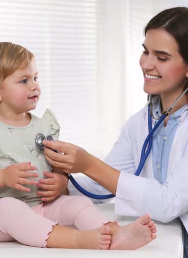 Pediatrician carrying out a checkup on a young child with a stethoscope. Pediatrician carrying out a checkup on a young child with a stethoscope.