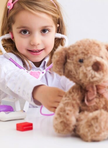 A young girl plays pretend doctor with a stethoscope and a teddy bear. A young girl plays pretend doctor with a stethoscope and a teddy bear.