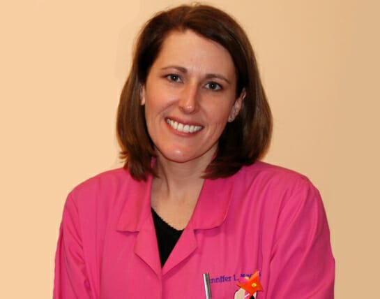 Woman in a pink uniform smiling at the camera.
