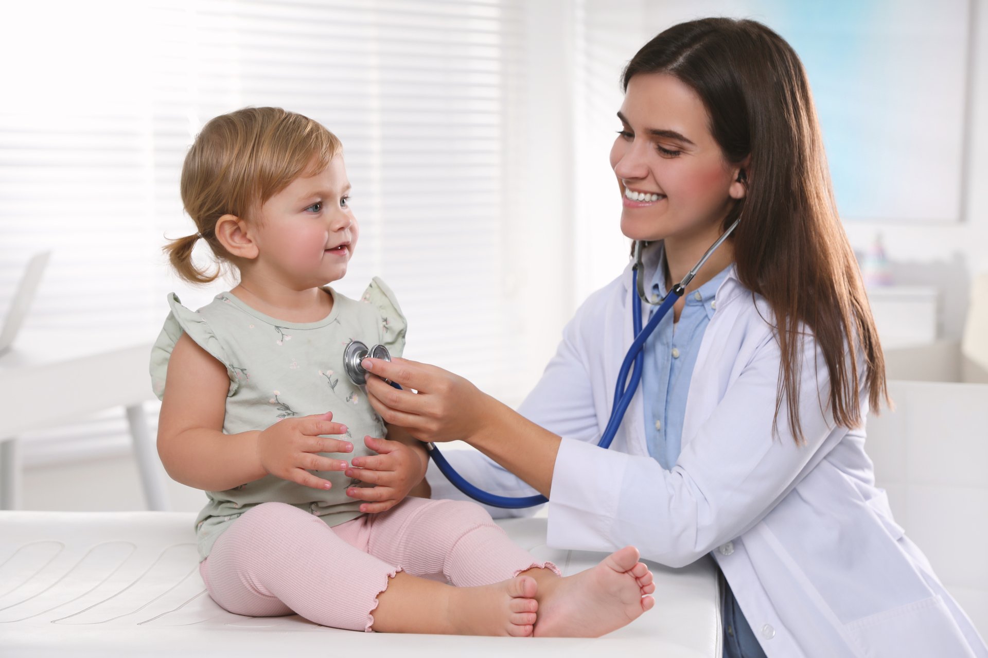 Pediatrician carrying out a checkup on a young child with a stethoscope.