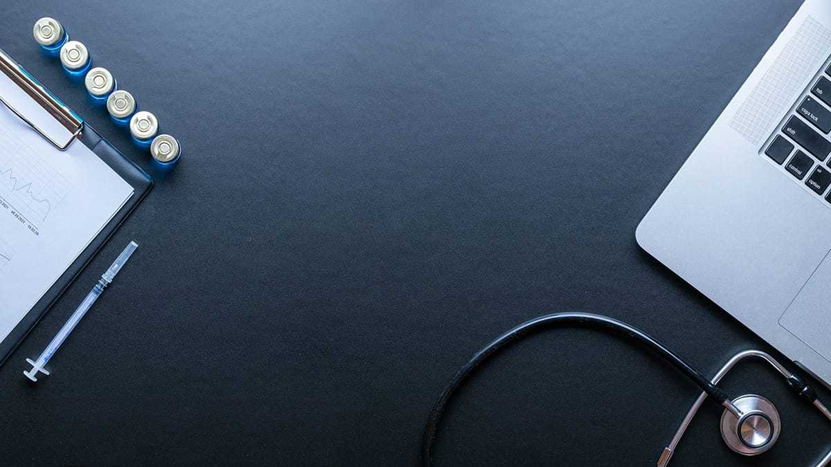 A stethoscope, laptop, clipboard with paper, and batteries arranged on a dark surface. A stethoscope, laptop, clipboard with paper, and batteries arranged on a dark surface.