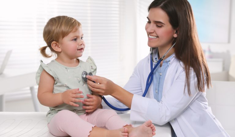 Pediatrician carrying out a checkup on a young child with a stethoscope. Pediatrician carrying out a checkup on a young child with a stethoscope.