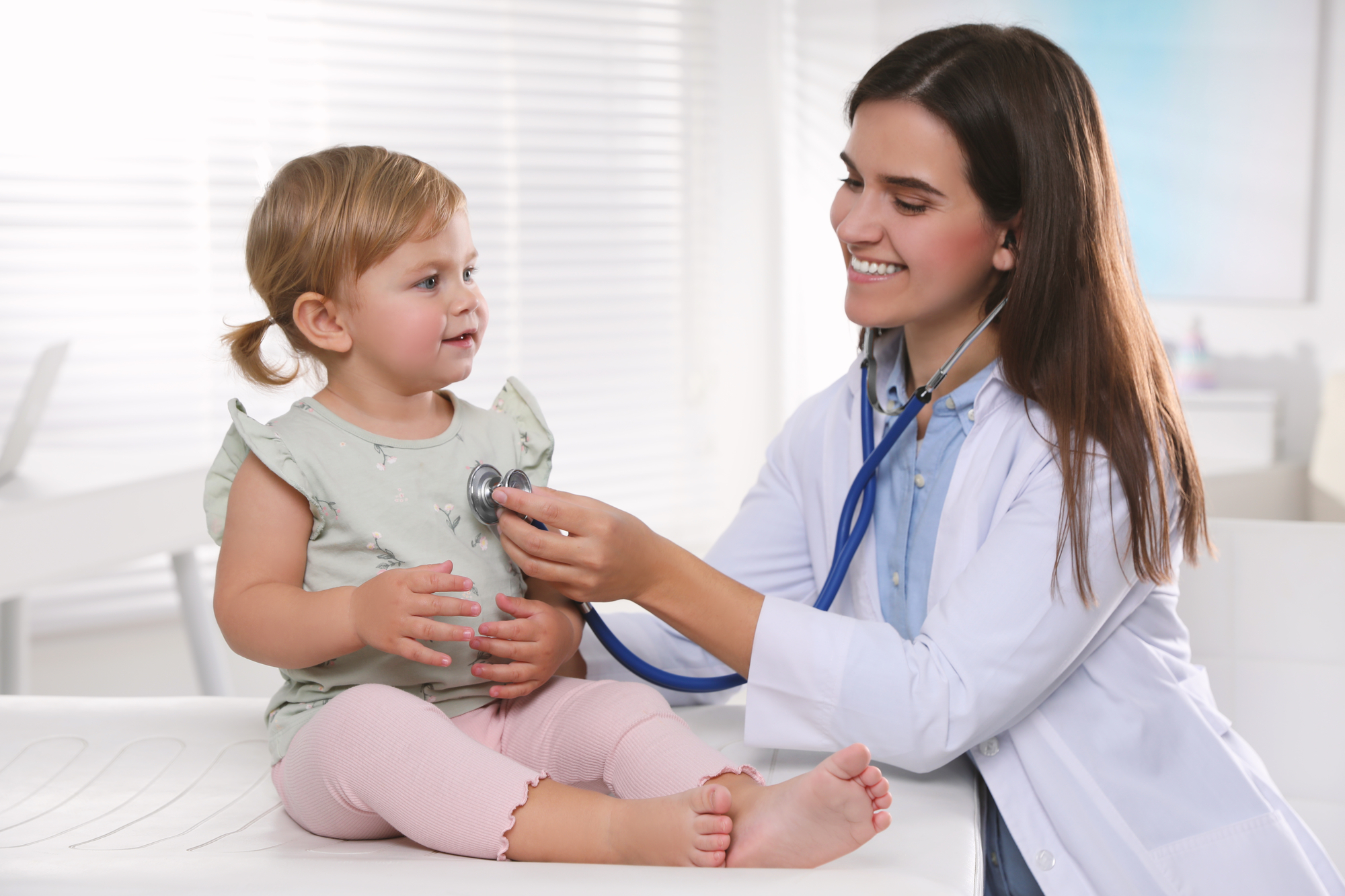 Pediatrician carrying out a checkup on a young child with a stethoscope.