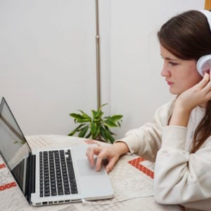 teenager study at home online with laptop and mobile and headphones