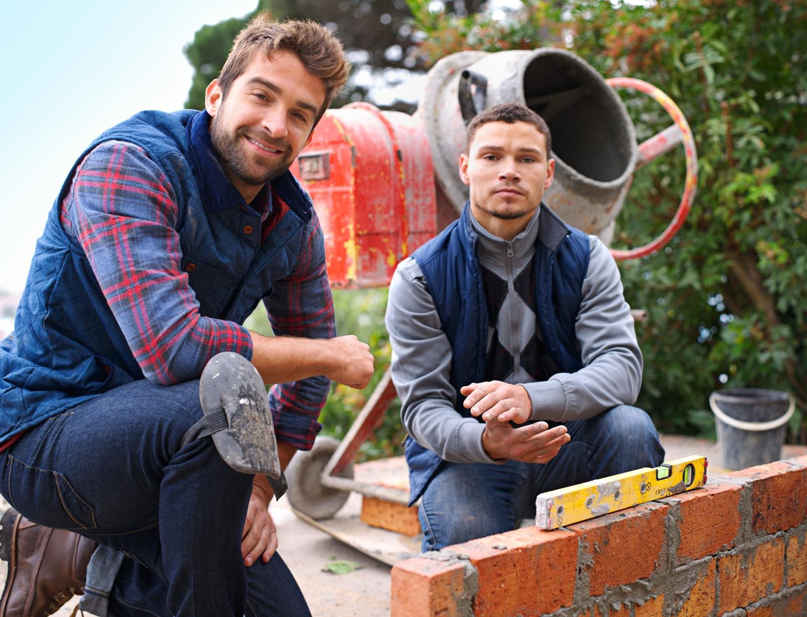 Making strong foundations. Portrait of a bricklayer and his apprentice at work.