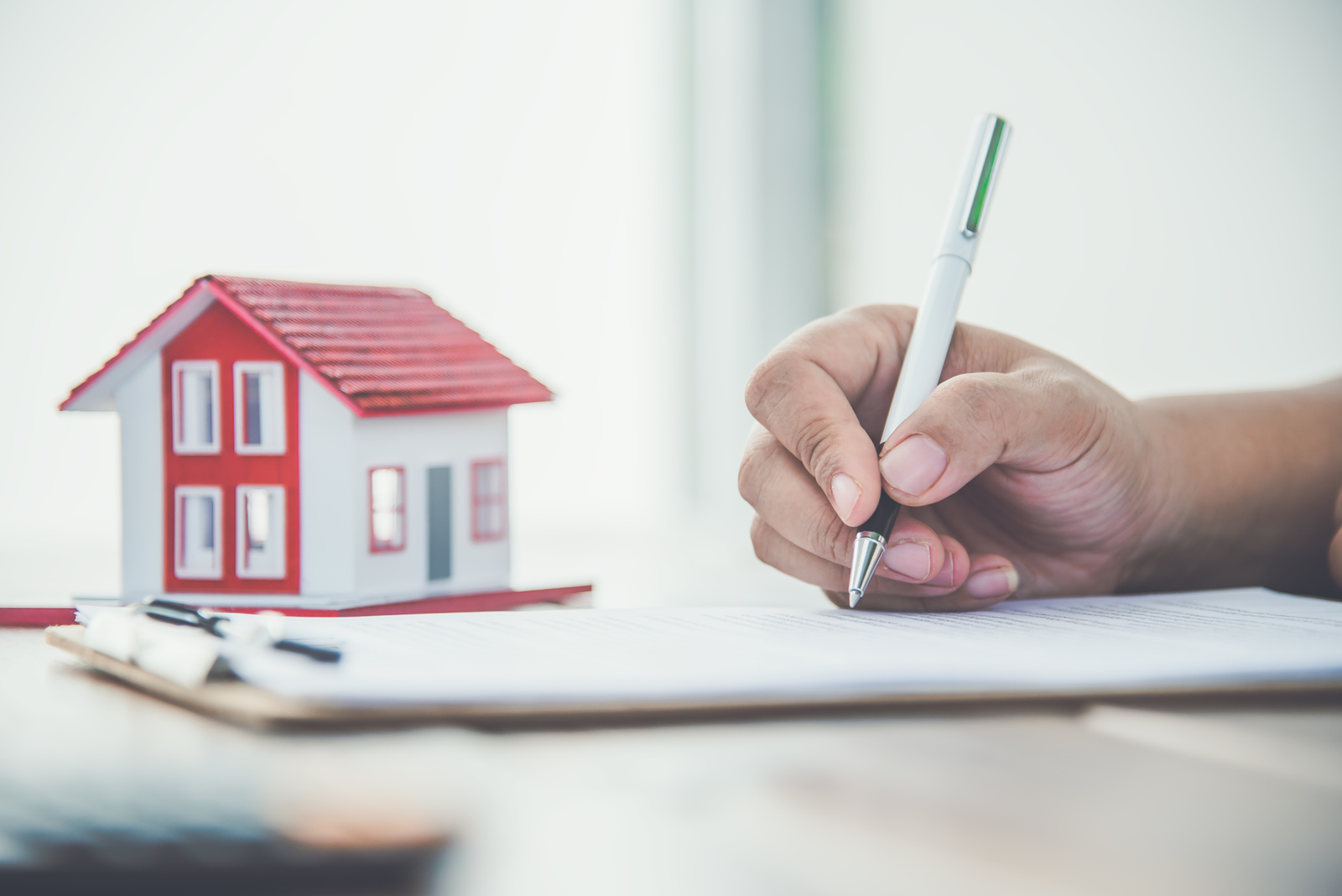 Close up hand signing signature loan document to home ownership. Mortgage and real estate property investment, home insurance ,security