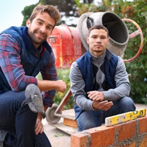 Making strong foundations. Portrait of a bricklayer and his apprentice at work.