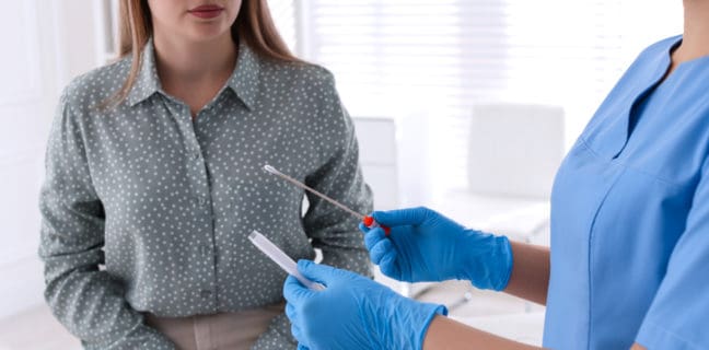 Risiken für sexuell übertragbare Infektionen senken Sexuelle Krankheiten, Doctor taking sample for STD testing from woman in clinic, closeup