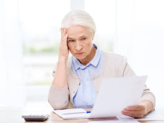 Betriebsrentner verlieren Anspruch an deutschen Arbeitgeber nach vereinfachter Sitzverlegung senior woman with papers and calculator at home