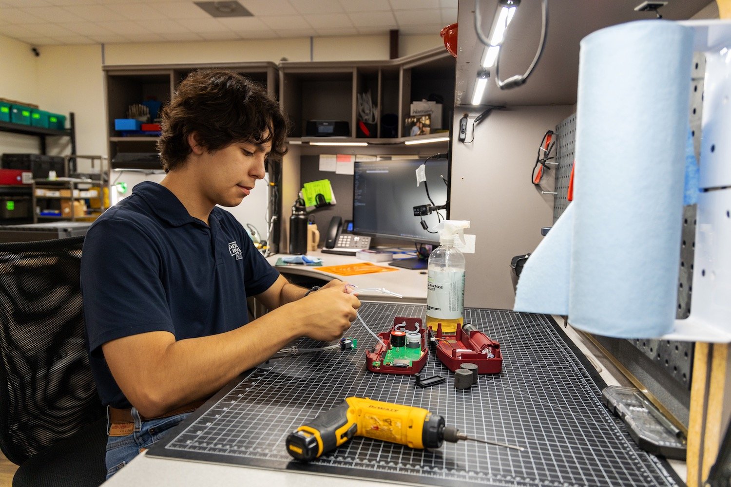Employee sitting at a desk with tools nearby cleaning to ensure the accuracy and reliability of a gas analyzer.