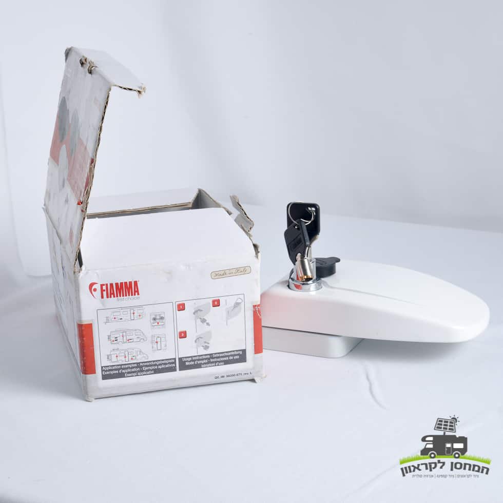 מנעול חיצוני לדלתות קרוואן מבית FIAMMA, לבן ומצויד במפתחות, מוצג לצד קופסת הקרטון הפתוחה שלו על משטח לבן. אביזר אידיאלי עבור קרוואנים המונעים על ידי שמש או מערכות קמפינג באנרגיה מתחדשת, תומך בתשתית מאובטחת למערכות פוטו-וולטאיות וייצור חשמל מחוץ לרשת.