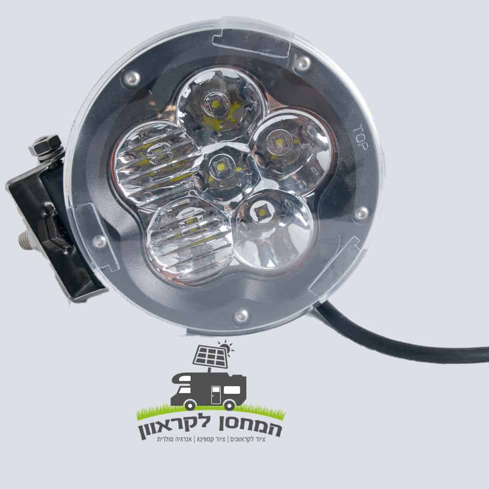 תקריב של פרוג'קטור עגול 6 לד 60W 12V, מנורת עבודה LED עגולה הכוללת מספר עדשות בעלות יעילות גבוהה ותושבת הרכבה יציבה, המיועדת לשילוב עם מערכות סולריות ופוטו-וולטאיות לשיפור פתרונות תאורה חסכוניים באנרגיה. המוצר מוצג על רקע אפור בהיר. להלן לוגו עם טקסט בעברית לצד משאית מאוירת המצוידת בפאנלים סולאריים, בדגש על מוצרים לקרוואנים ולמחנאות התומכים בייצור אנרגיה מתחדשת ותשתית בת קיימא.