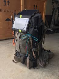 תרמיל טיולים ארוז במלואו ניצב בתוך הבית על רצפת בטון לצד סוללת גיבוי קומפקטית VENTURE30 בהספק IPX6 של 28Wh, הכוללת טכנולוגיה תואמת סולארית לייצור חשמל מחוץ לרשת החשמל ואחסון אנרגיה מתחדשת באמצעות תשתית פוטו-וולטאית ניידת.