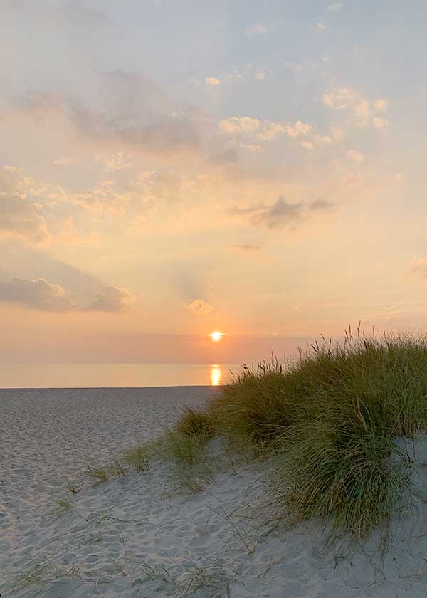 Solen er lige ved at ramme havet, den sarte rosa og blå himmel emmer af en sommerdag der går på hæld