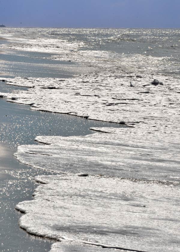 Vandet slår stille ind på stranden i den nedgående sols stråler efter en dejlig sommerdag