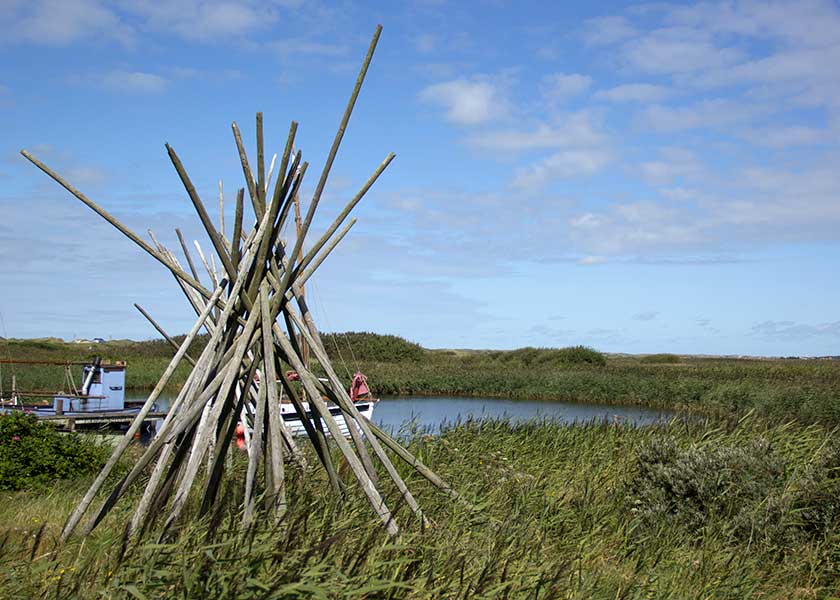 Rusepælene står stakkede op, her ved havnen i Nymindegab i baggrunden et par fjordjoller