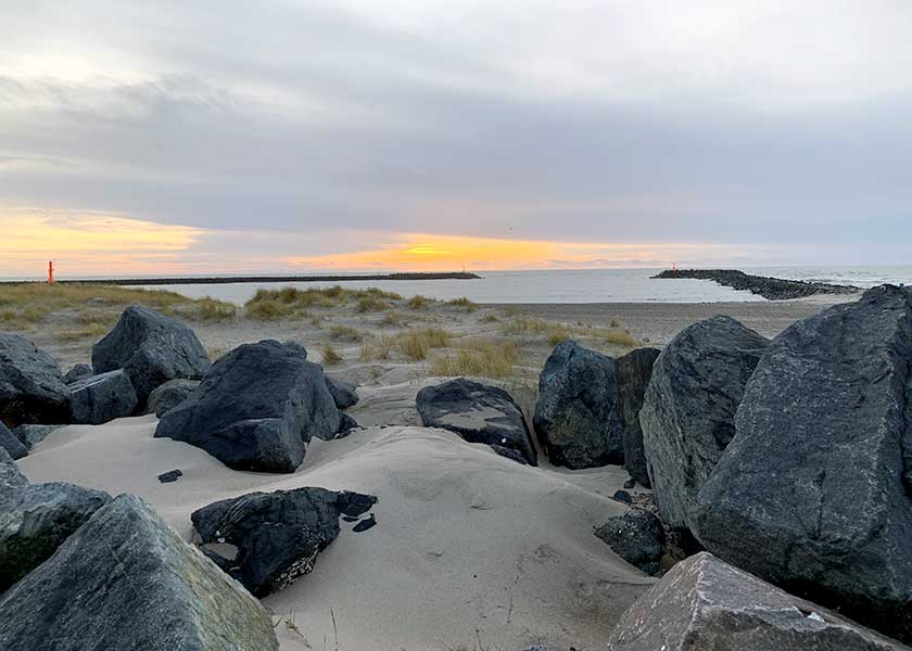 Indsejlingen til Hvide Sande mellem molerne på nordstranden - det er en stille sommeraften hvor solen tegner det sidste spæde lys på himlen