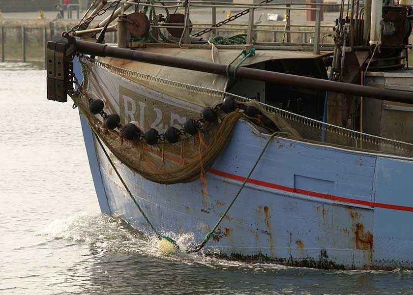 Den sidste rejekutter i træ steamer ud af havnen på vej på nattens fiskeri