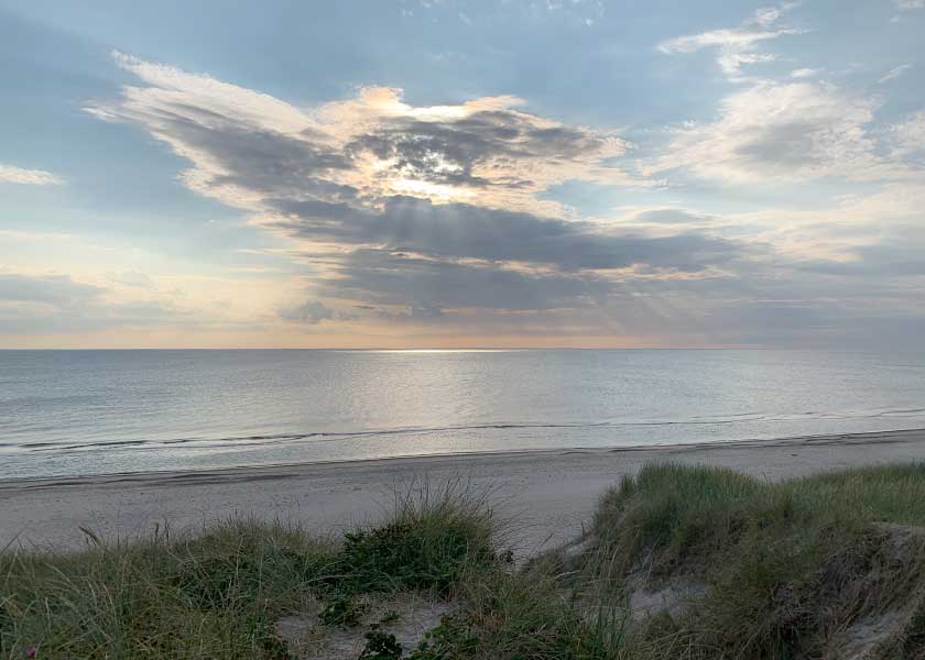 Den nedgående sol tegner flotter mønster mod himlen når strålerne brydes gennem de store cumulus skyformationer