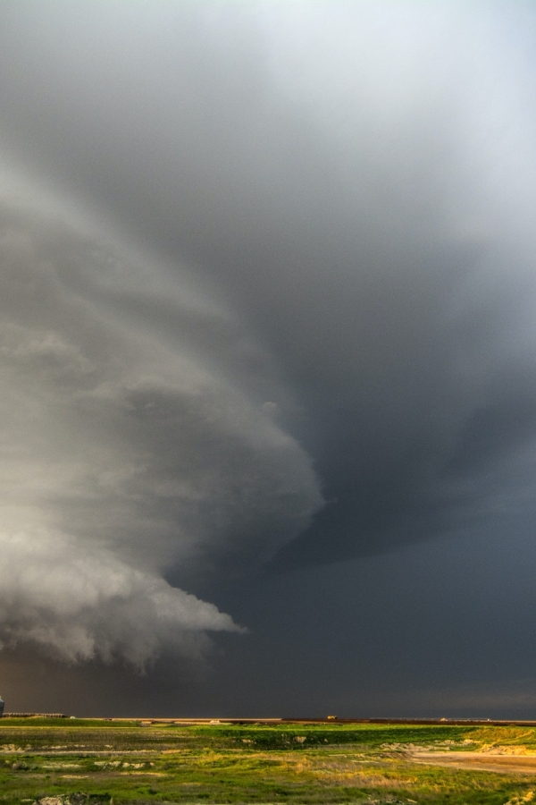 A tornado-producing supercell thunderstorm spinning over ranch land at sunset near Leoti, Kansas