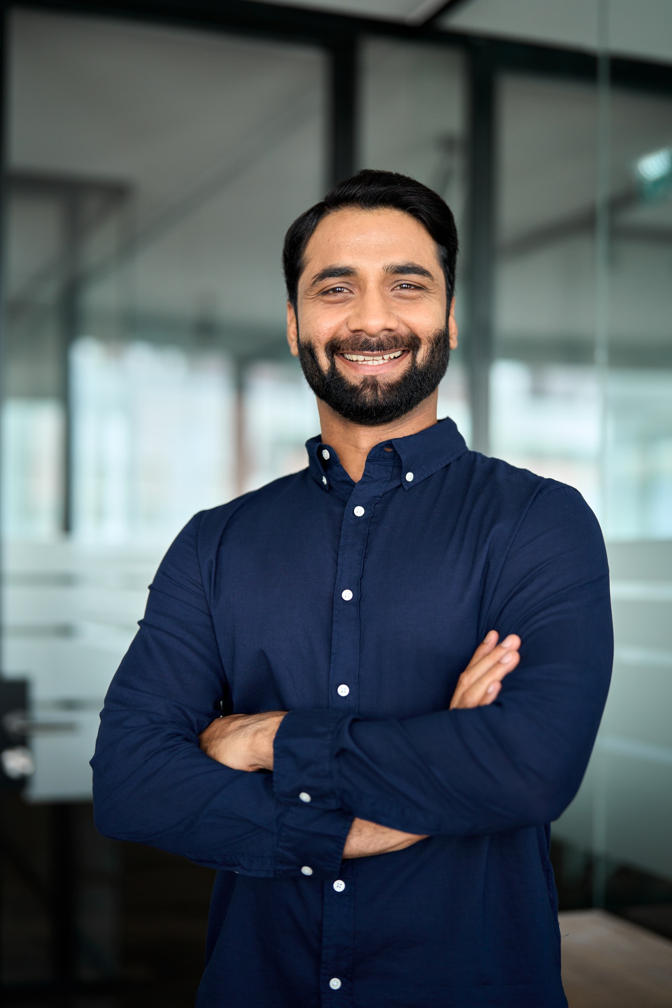 Happy Indian business man professional standing in office. Vertical portrait.
