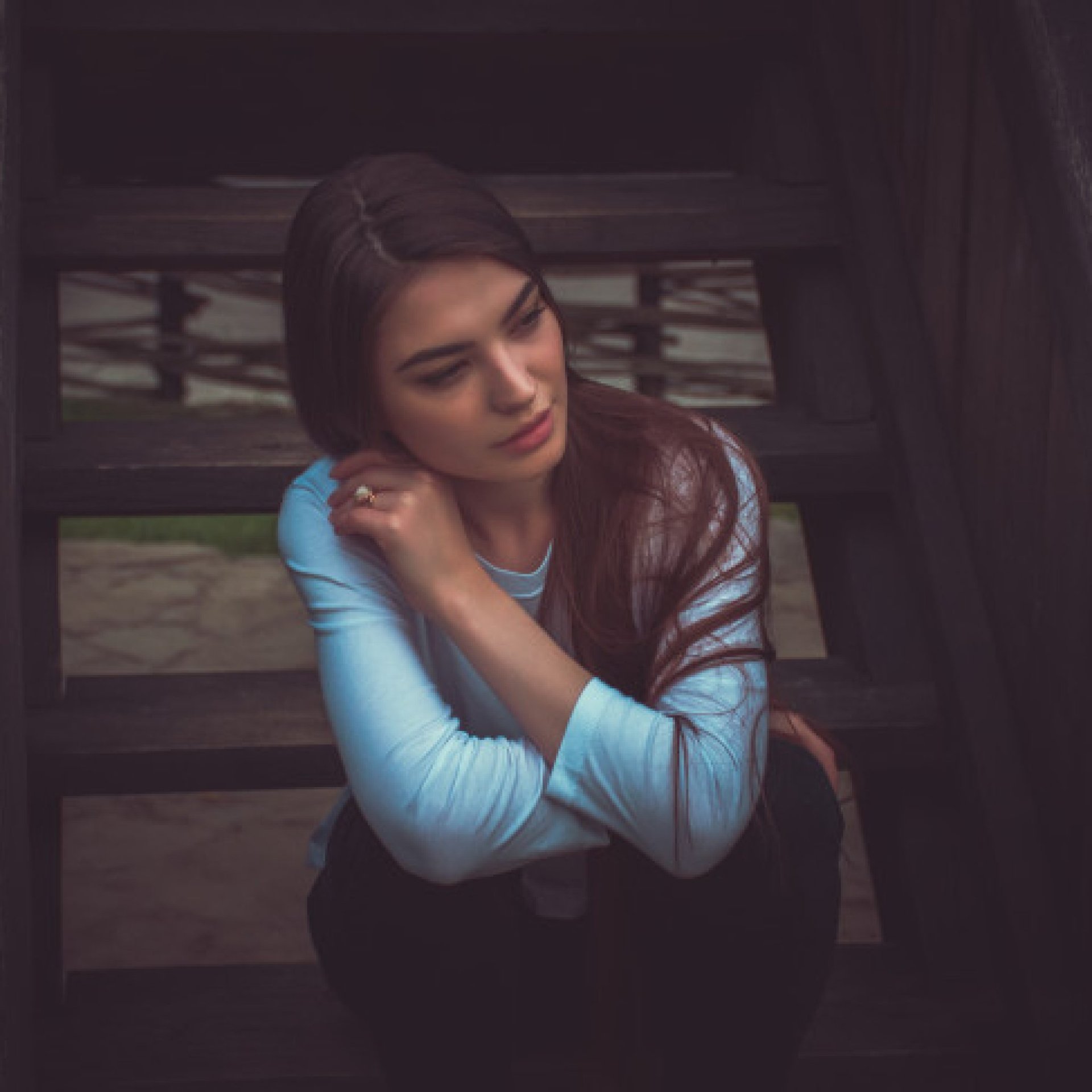 A young woman sitting on the steps of a wooden building.