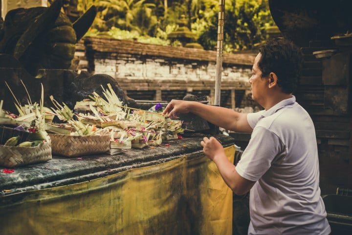 A man putting flowers on a table in front of a temple.