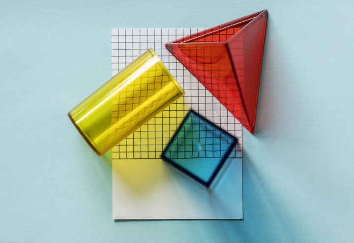 Picture a red triangle, yellow cylinder, and a blue cube on a flat white piece of paper symbolical representing dimensions that can be found in life. This pic is for the dimensions category for No Relent TV