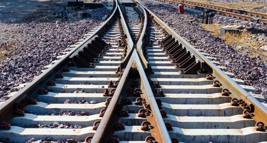 A pair of train tracks in the middle of a field, serving as a transportation route for trains.