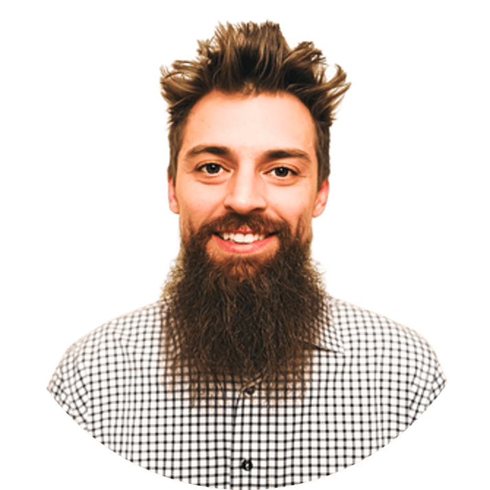 Man with a full beard and mustache, wearing a checkered shirt, smiling at the camera against a plain background.