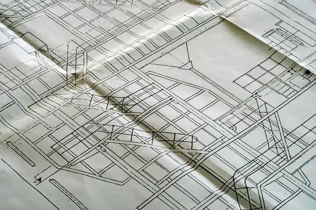 A close-up view of a detailed architectural blueprint with technical line drawings and construction plans on white paper.
