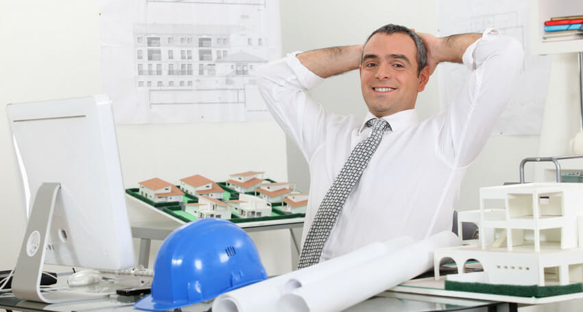 A civil engineer with a hard hat in front of a model of a building.