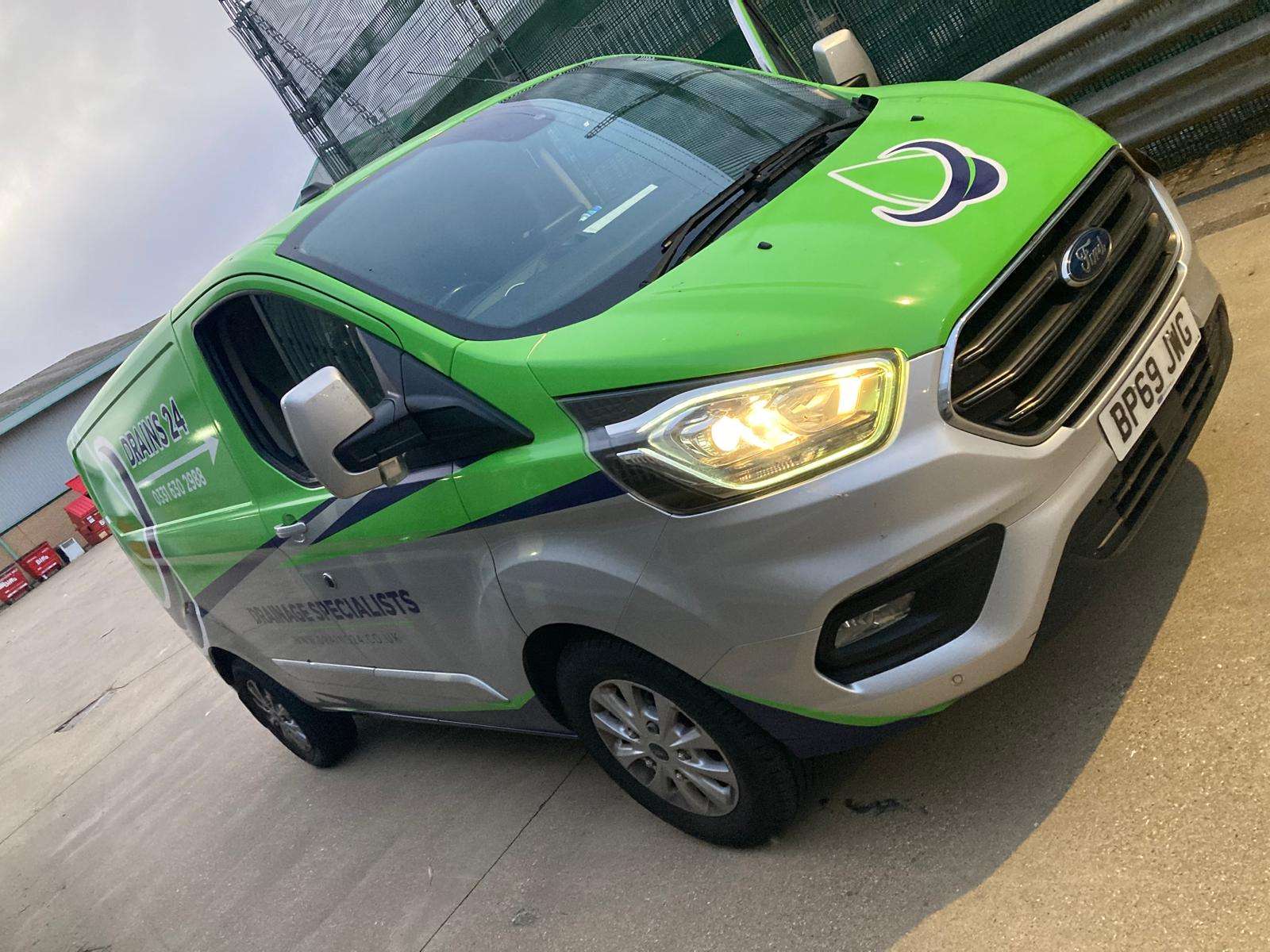 A technician performing commercial drain cleaning in a Southampton restaurant kitchen using high-pressure jetting equipment near stainless steel drains.