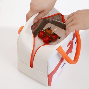 Sac isotherme avec fermeture éclair, conçu pour garder les aliments au frais, avec des poignées orange et un intérieur isolant, contenant des tomates.