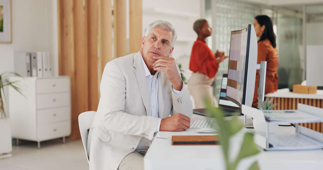 A man sitting at a desk ensuring security compliance and reviewing FTC safeguards on his computer.