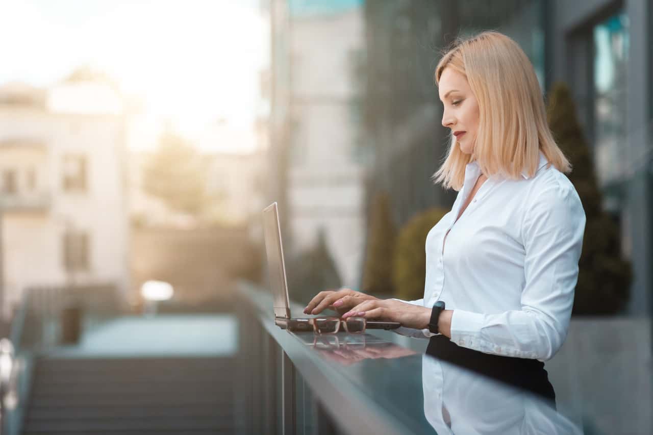 A business woman utilizing cyber security measures while working on her laptop on a balcony.
